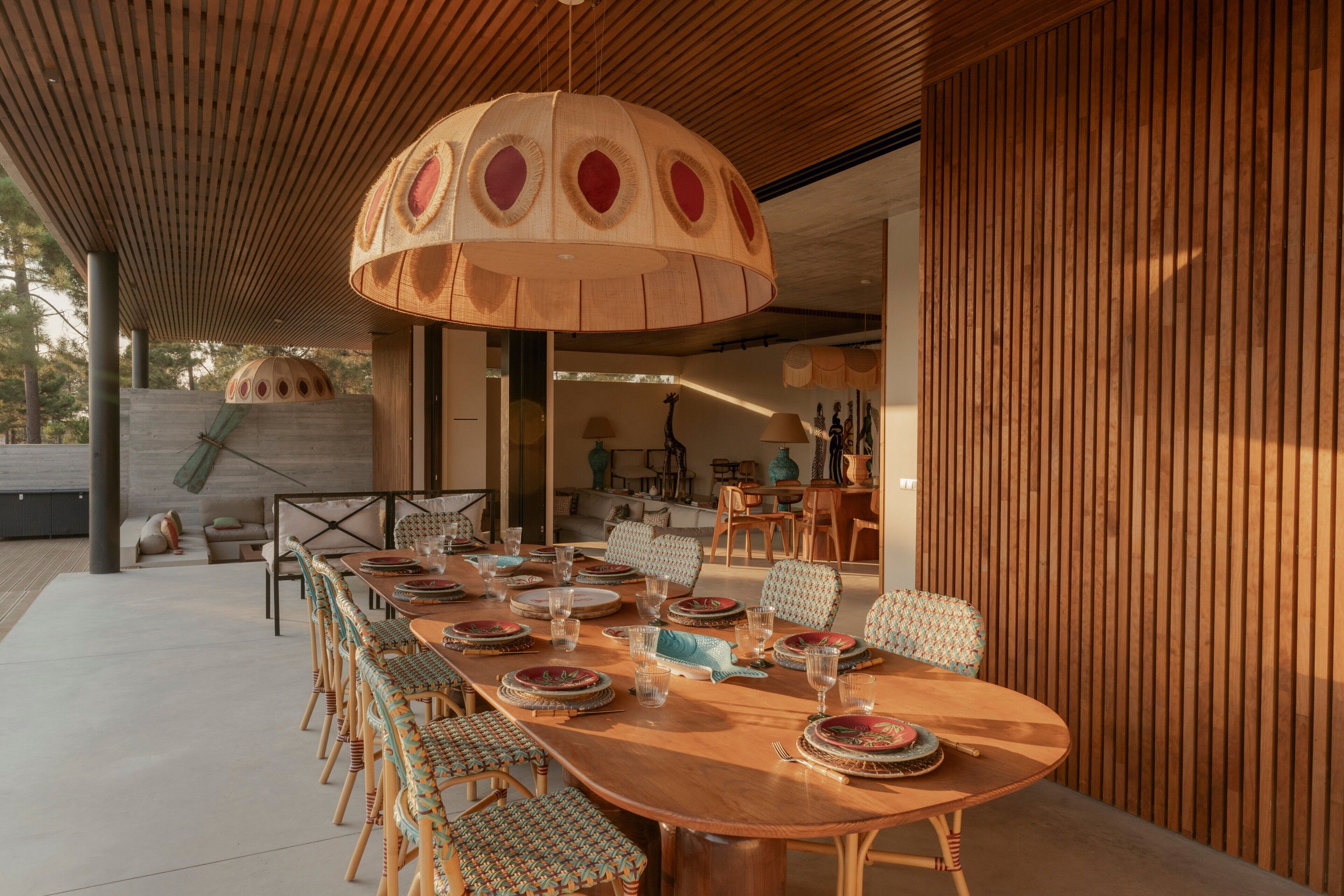 Un espace de restauration en plein air avec une longue table en bois, des chaises et un grand parasol.