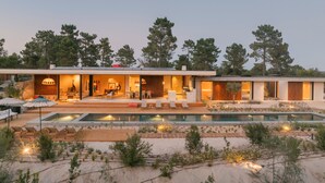 Una casa moderna con piscina, mobiliario exterior y un jardín cuidado.