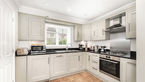 A modern kitchen with white cabinets, a stainless steel stove, and a black countertop.
