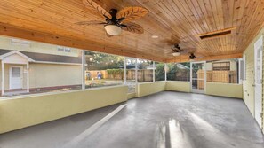 Un espacio de patio cubierto con suelo de concreto, techo de madera y amplios ventanales.