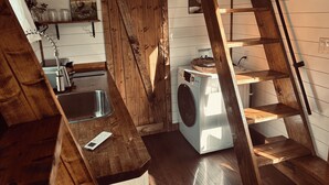 Een kleine wasruimte met een wasmachine, een wasbak en een houten ladder.