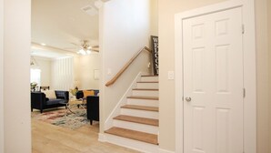A staircase with a 'WELCOME' sign, a living room with a sofa and coffee table, and a door. - Fabulous 2-bedroom in a Prime location, Houston Medical center and NRG stadium! (Houston)