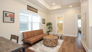 A living room with a brown sofa, a round coffee table, and a framed basketball artwork. - Fabulous 2-bedroom in a Prime location, Houston Medical center and NRG stadium! (Houston)