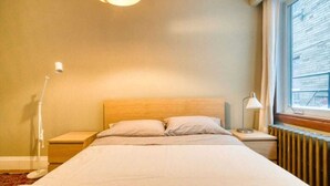Une chambre à coucher avec un lit, des tables de chevet, une lampe et une fenêtre.