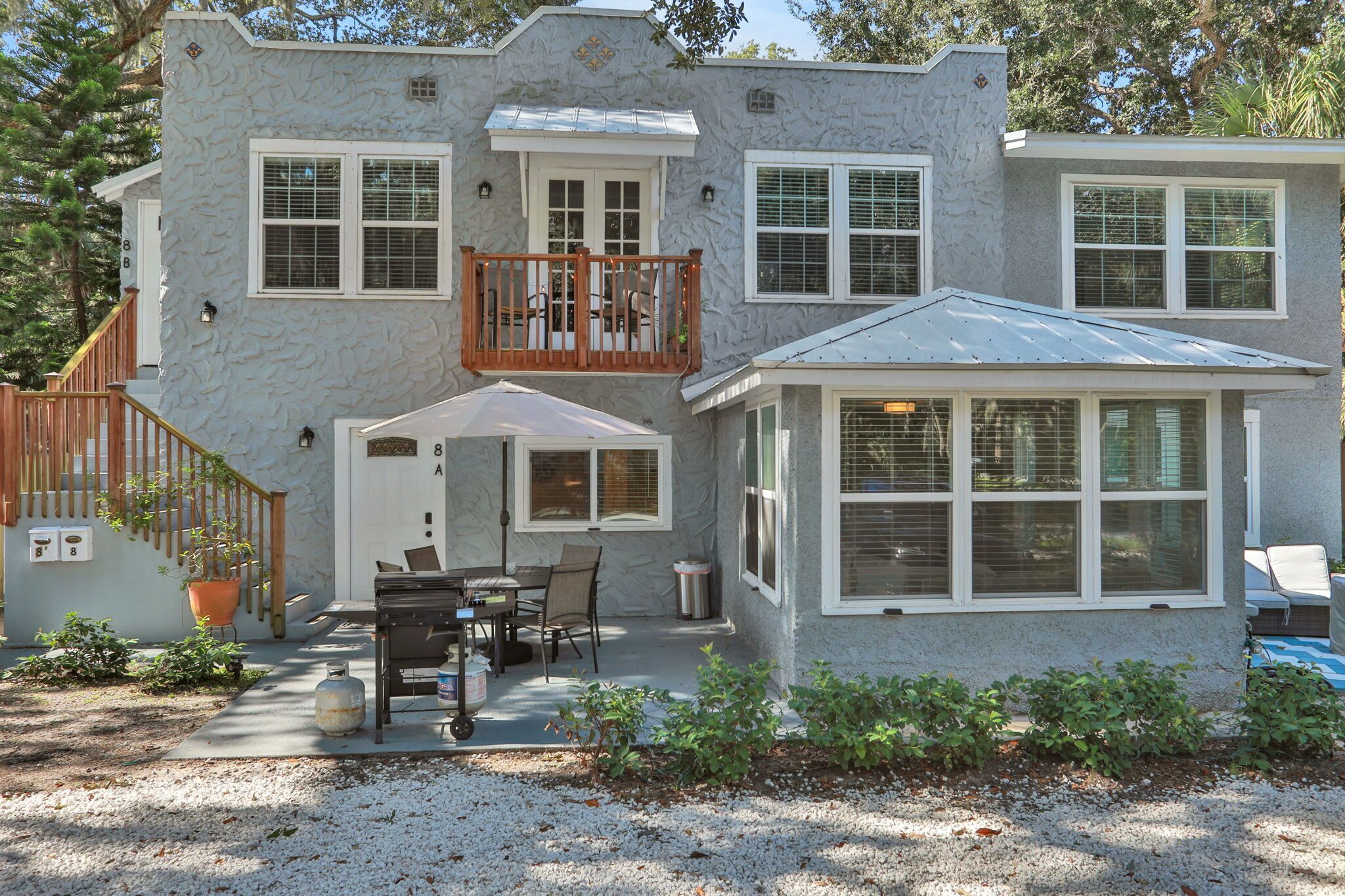 A two-story house with a balcony, a covered patio, and a small attached garage.
