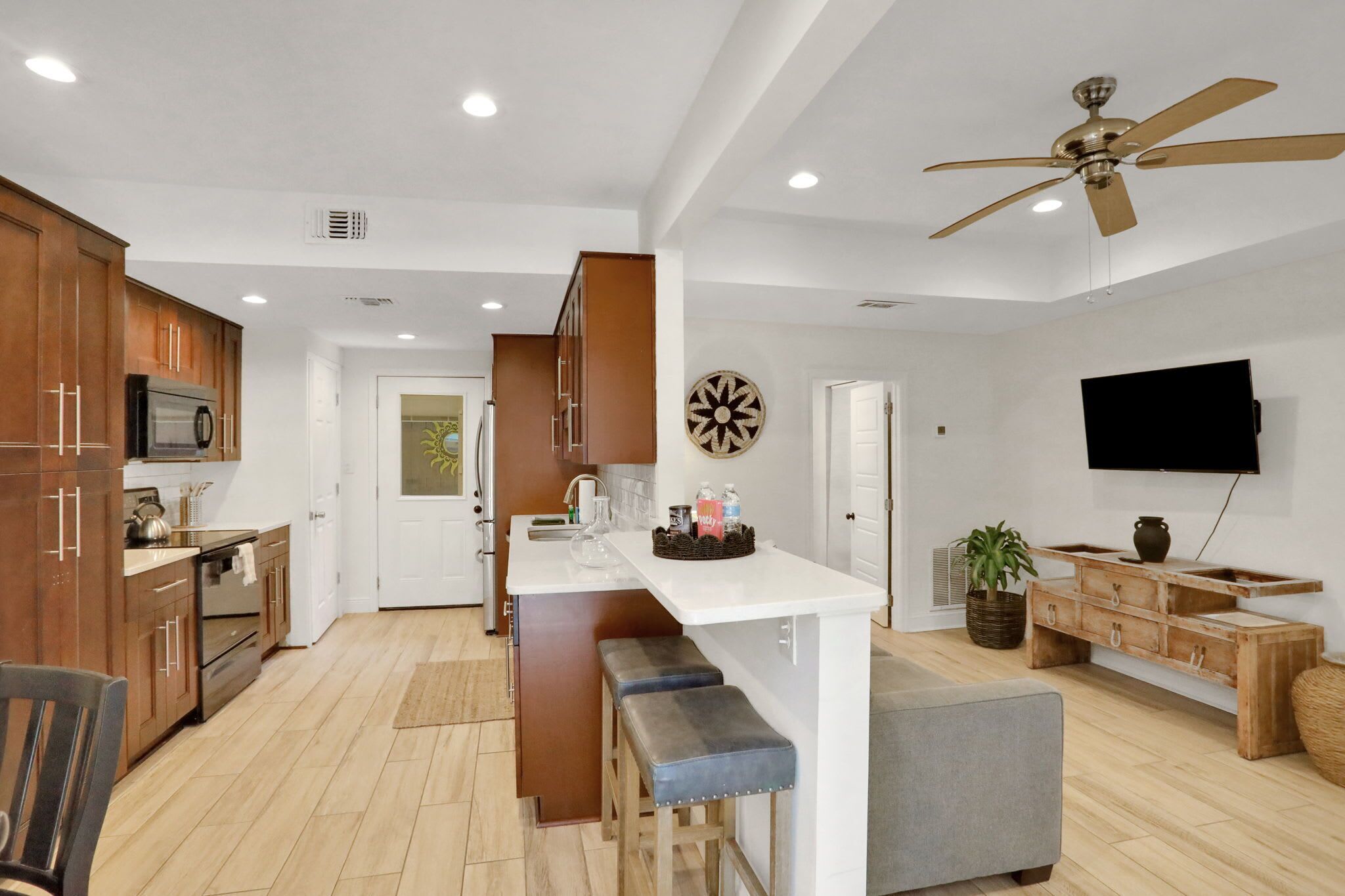 A modern kitchen with wooden cabinets, a central island, and a ceiling fan.