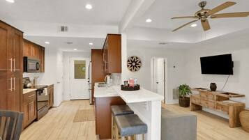 A modern kitchen with wooden cabinets, a central island, and a ceiling fan.