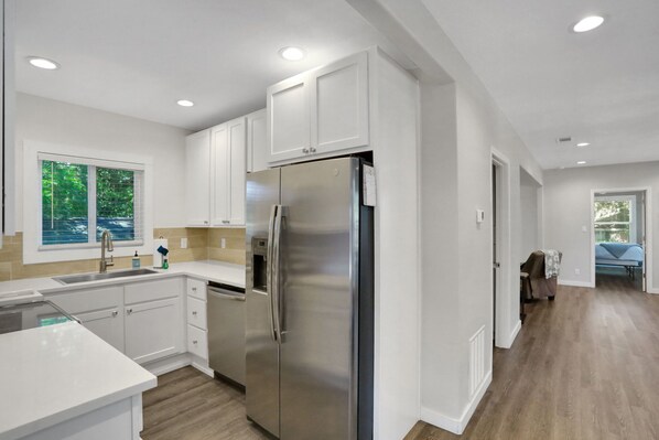 A modern kitchen with white cabinetry, stainless steel appliances, and a wooden floor. - Paradise in St Augustine B (St. Augustine)