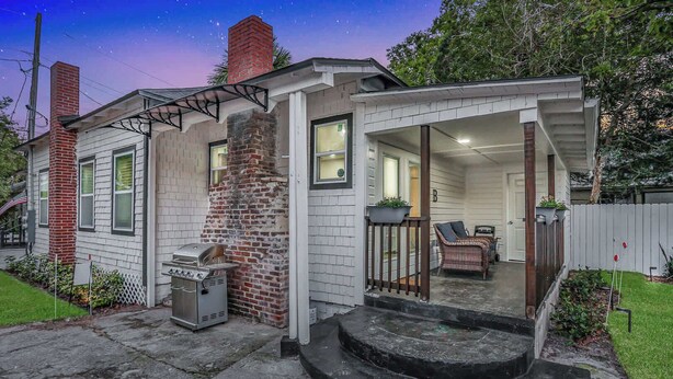 Einbungalow mit Ziegelkamin, einer Veranda und einem Grill vor der Fassade.