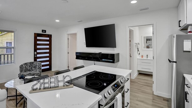 Una cocina moderna con estufa integrada, televisor de pantalla plana y refrigerador.