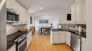 Uma cozinha moderna com armários brancos, bancada preta e painel de azulejos.