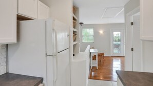A kitchen with white cabinets, a refrigerator, and a dining area with a table and chairs.