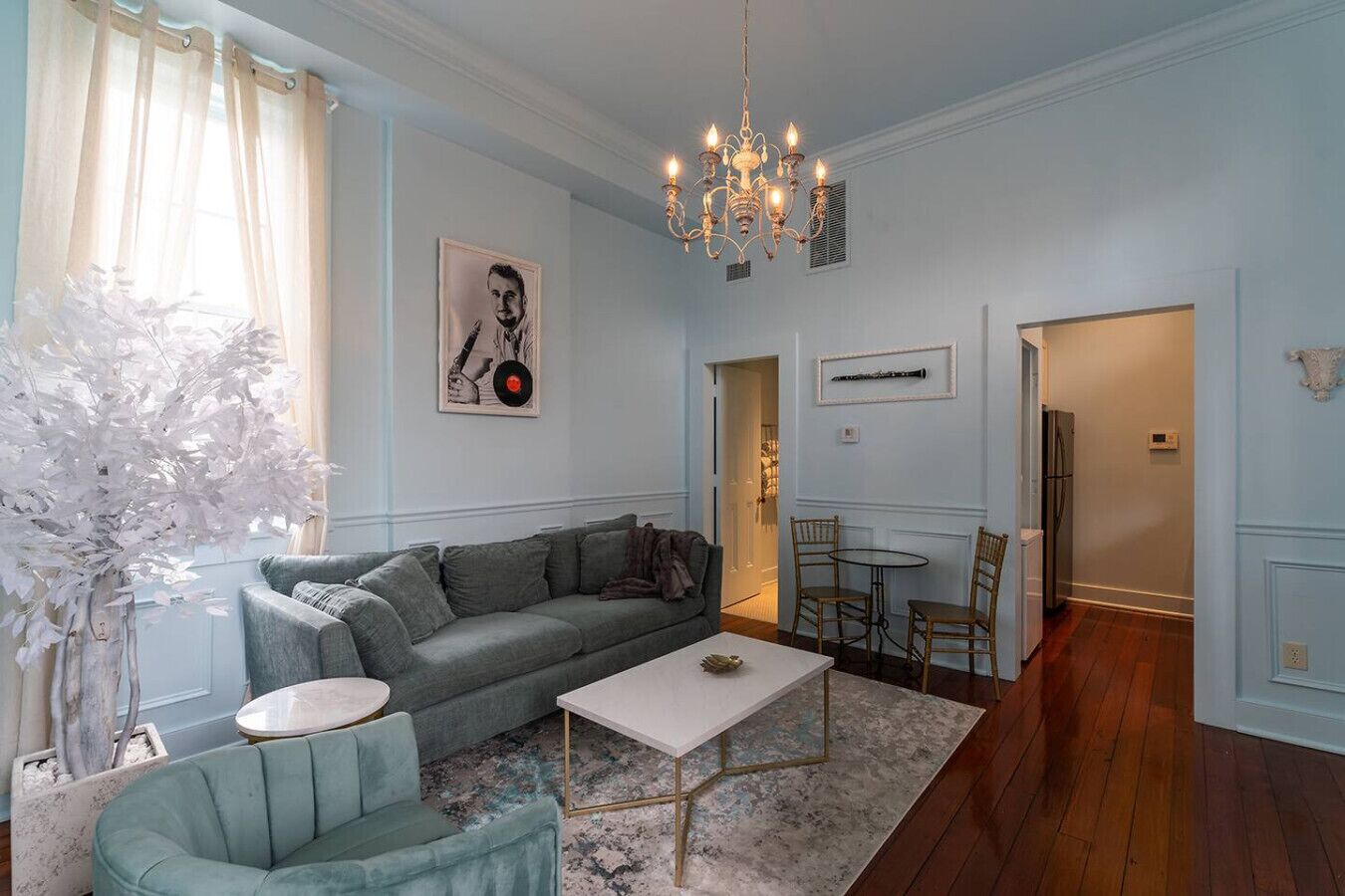 A living room with a grey sofa, a white coffee table, and a chandelier.