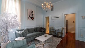 Una sala de estar con un sofá gris, una mesa de centro blanca y una araña.