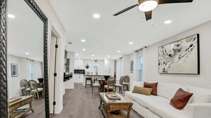 Amplia sala de estar con un sofá blanco, una mesa de centro y una mesa de comedor con sillas.