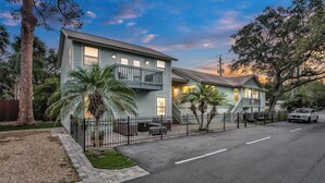 A row of two-story houses with a balcony, a paved driveway, and a car parked on the street. - Historic Downtown Casita A (St. Augustine)