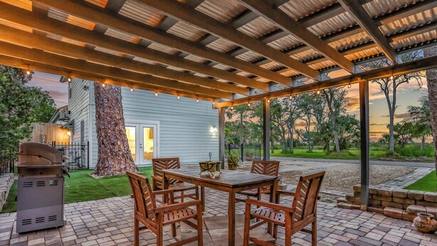 An outdoor patio with a wooden table and chairs, a grill, and a pergola with string lights. - Historic Downtown Casita A (St. Augustine)