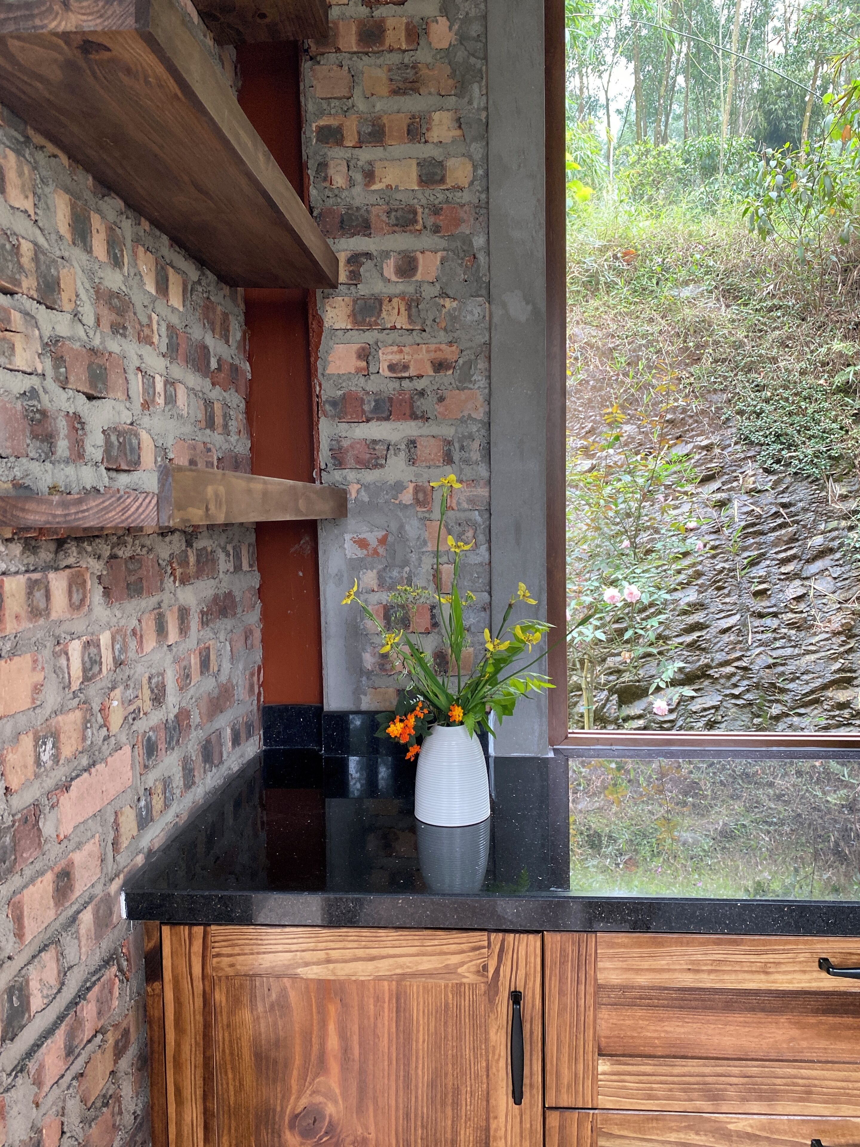 Cocina con pared de ladrillo, armarios de madera y encimera negra.