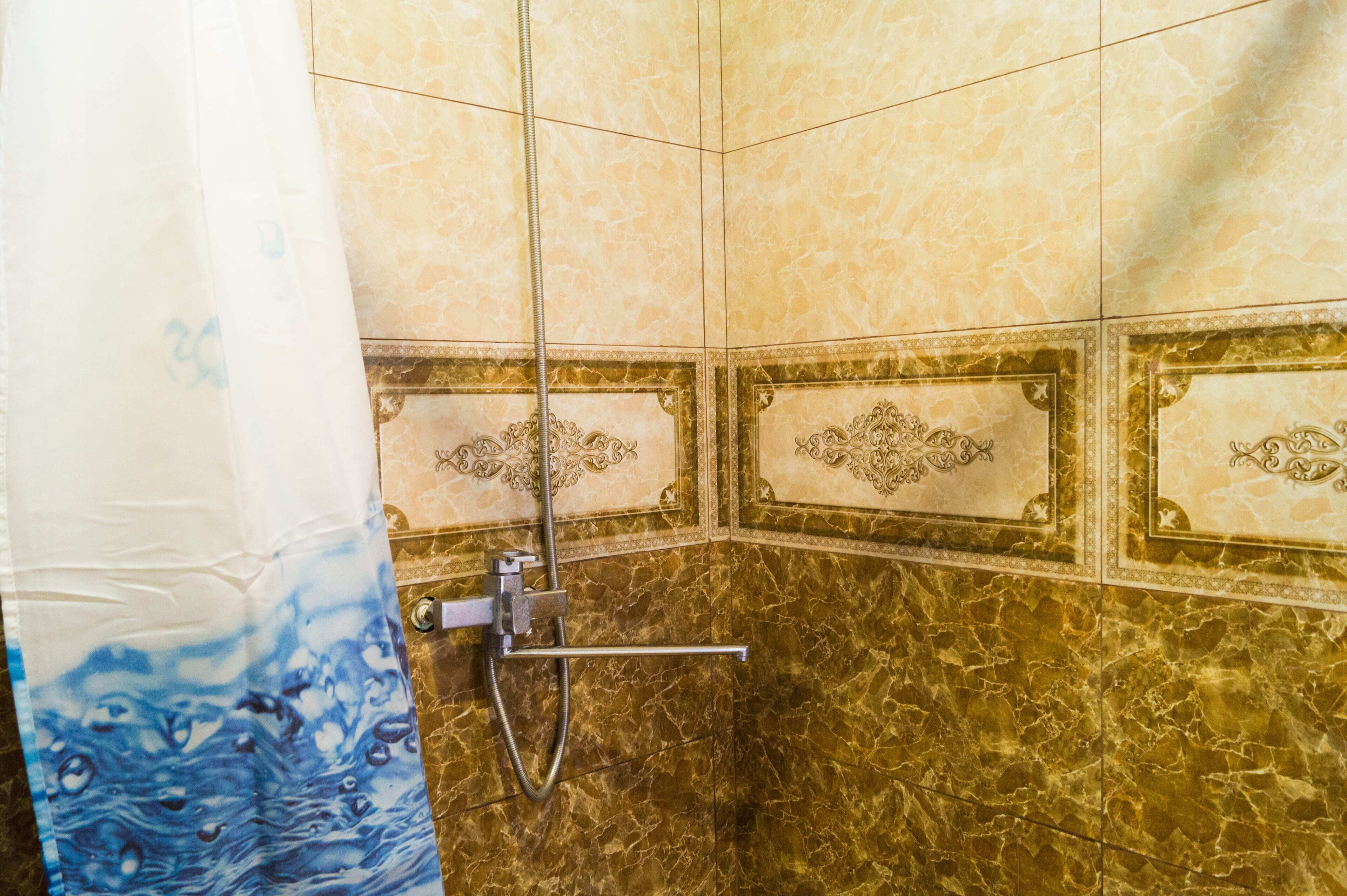 A bathroom with a shower, tiled walls, and a curtain.