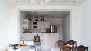 Une cuisine moderne avec des meubles blancs, un réfrigérateur en acier inoxydable et un coin repas comprenant une table et des chaises blanches.