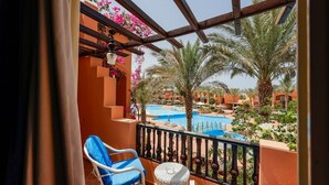 Ein Balkon mit Blick auf einen Swimmingpool und Palmen.