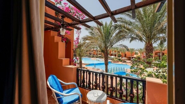 Ein Balkon mit Blick auf einen Swimmingpool und Palmen.
