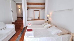 A hotel room with a bed, a sofa, a small table with a lamp, and a mirror. - Gorgeous 1-bedroom cottage in peaceful Lagoa (Lagoa)
