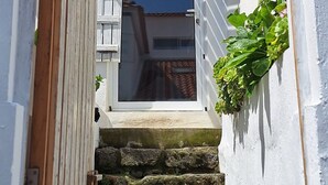 A narrow staircase leading to a white door with a wooden door frame and a small window above it. - Gorgeous 1-bedroom cottage in peaceful Lagoa (Lagoa)