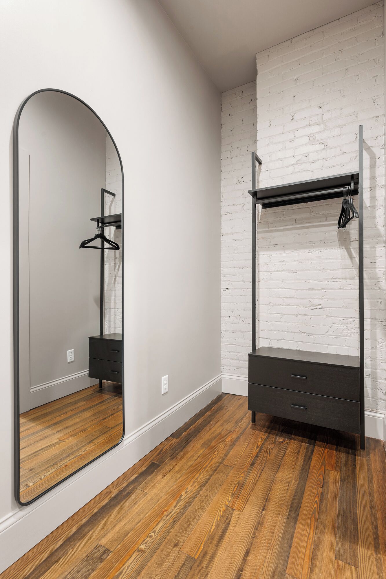 A room with a large mirror, a wardrobe, and a hanging rack.