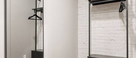 A room with a large mirror, a wardrobe, and a hanging rack.