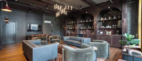 A modern living room with a large gray sofa set, a coffee table, and a bar area with shelves of bottles and glasses.