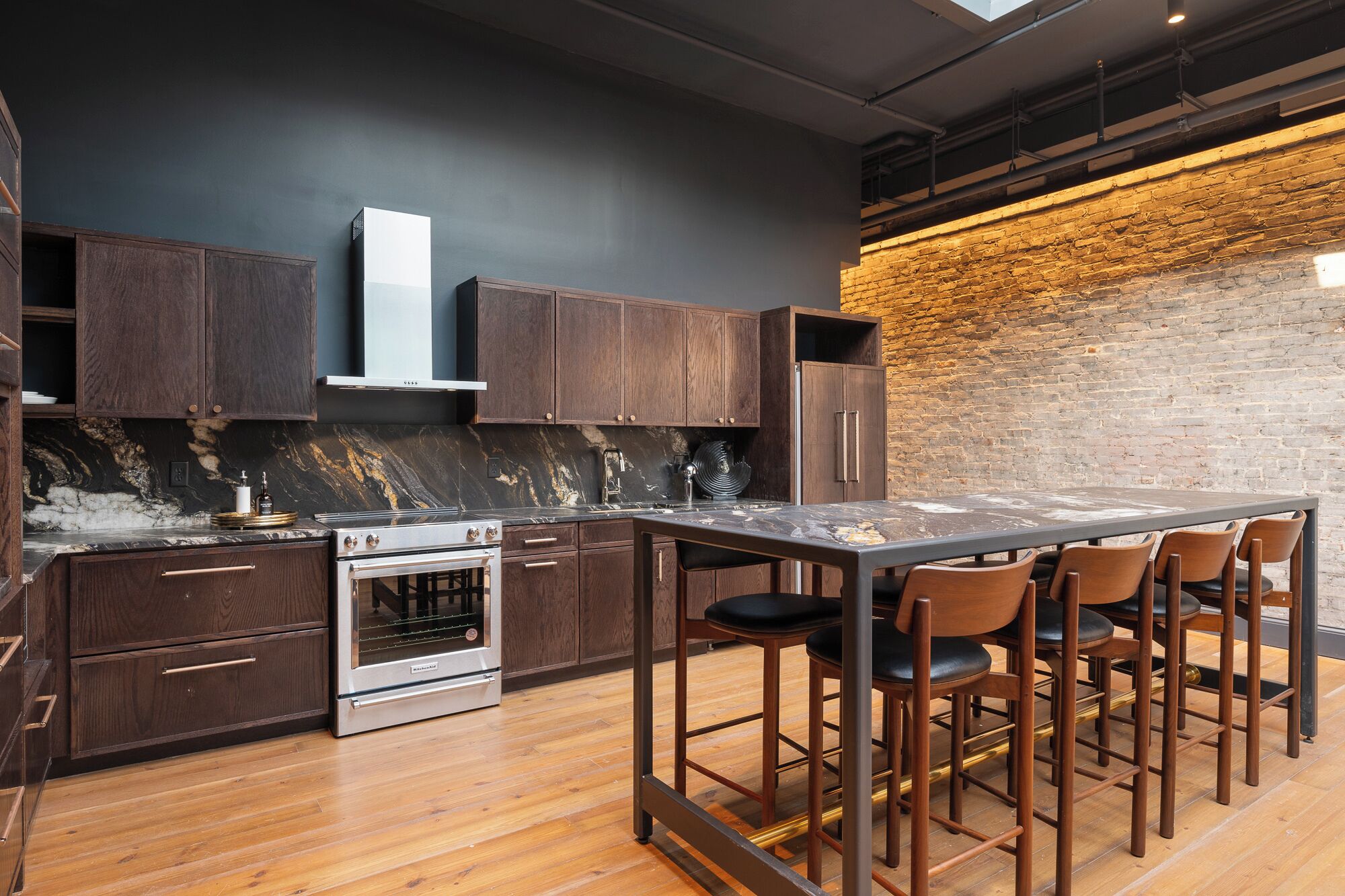 A modern kitchen with dark wood cabinets, a stainless steel range, and a marble countertop.