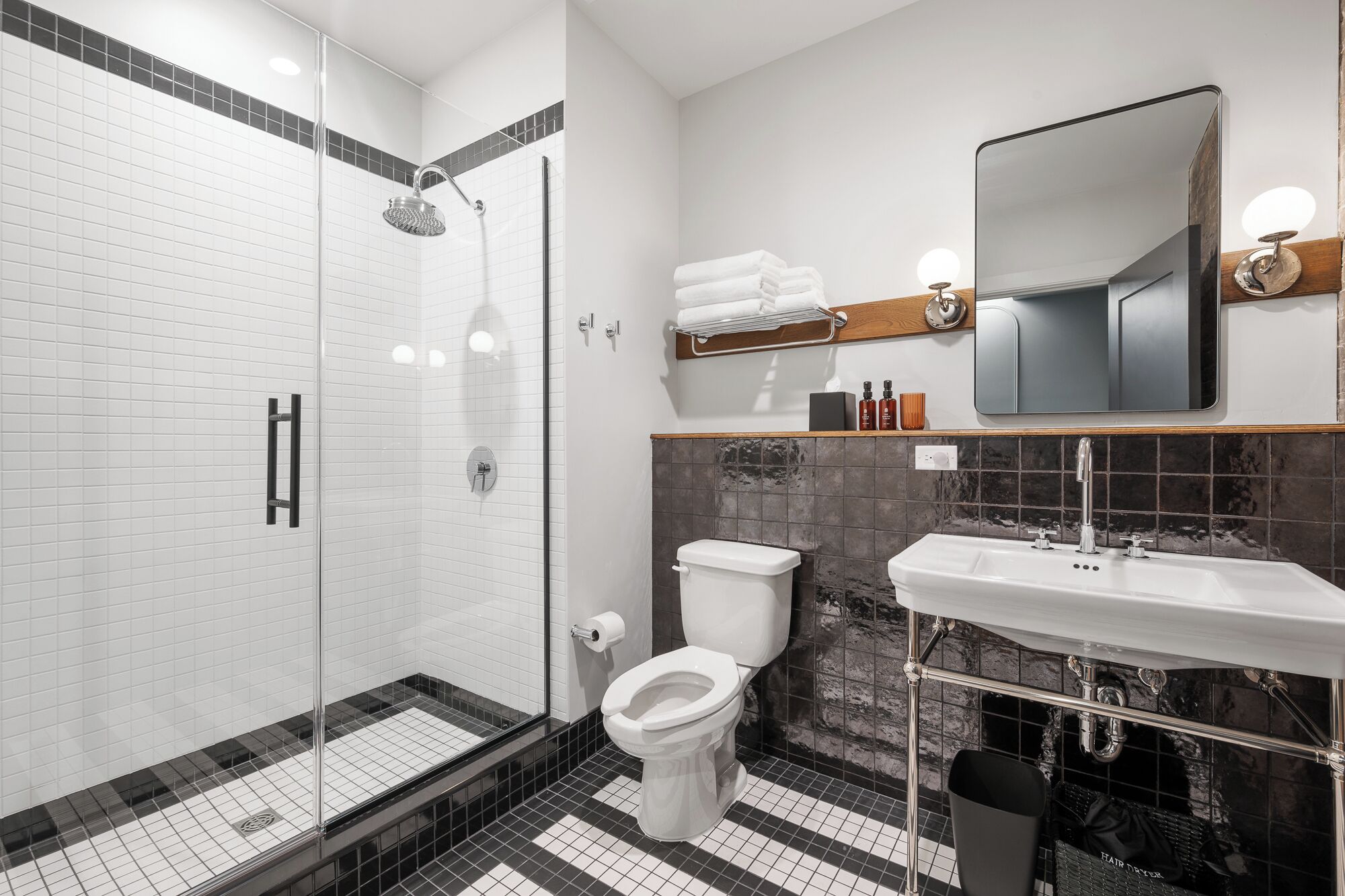 Un baño moderno con ducha de vidrio, inodoro, lavabo y espejo.