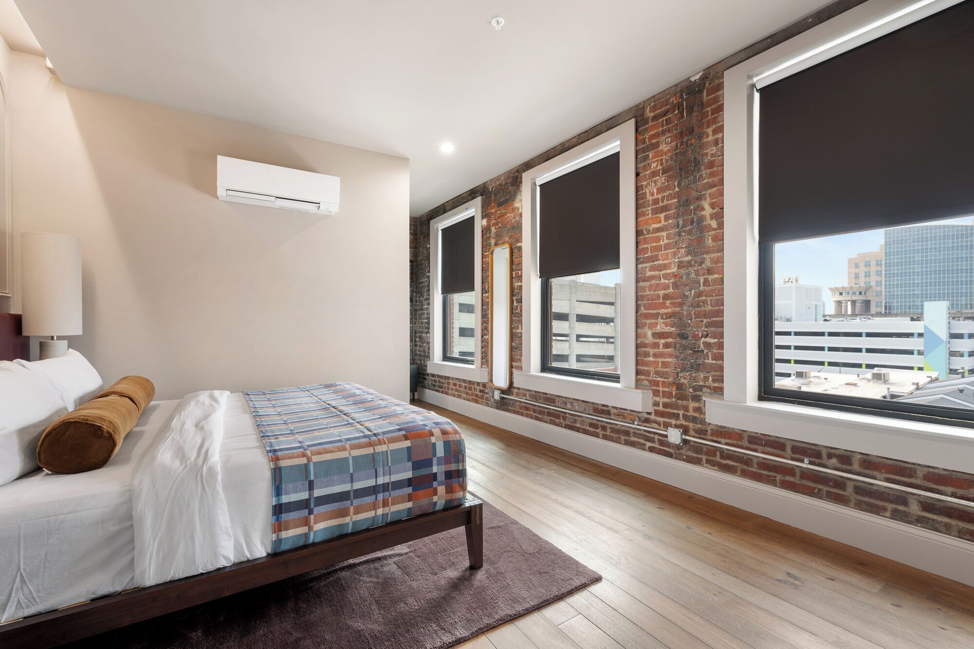 A bedroom with a bed, a large window, and a view of the city.