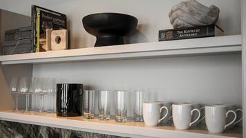 A shelf with books, a black bowl, and a sculpture.