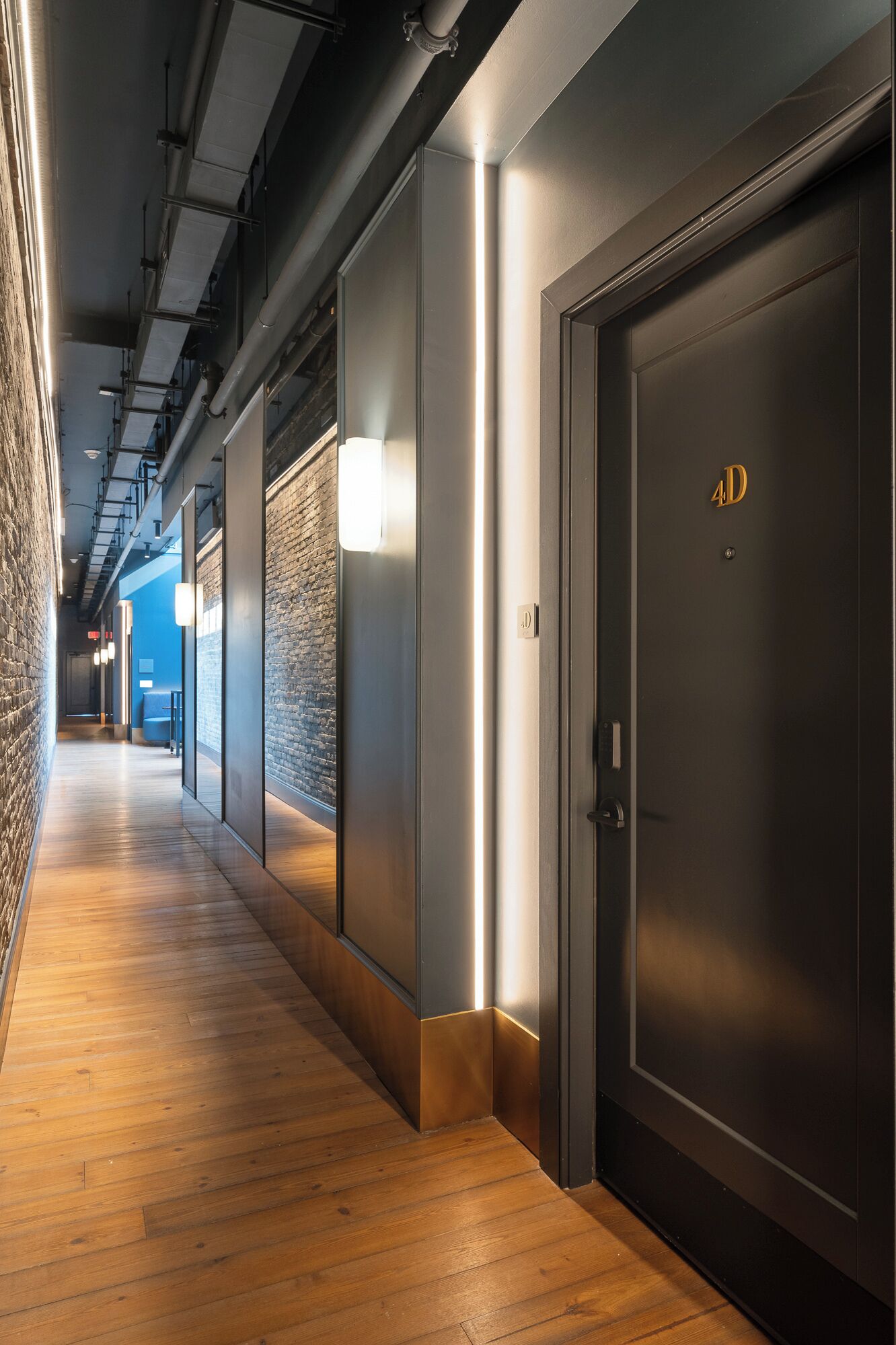 A hallway with wooden flooring, a brick wall, and a door marked with '4D'.