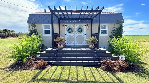 A house with a covered porch, two front doors with wreaths, and a number '25' on the door.