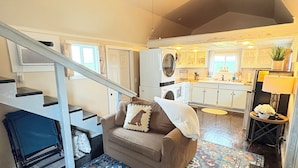 A cozy living room with a brown sofa, a patterned rug, and a ceiling fan.