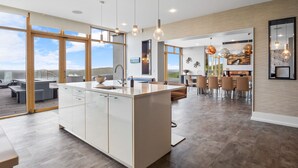 A modern kitchen with a central island, large windows, and a dining area with a view. - Suaimhneas Villa with Castle and Sea Views (Clifden)