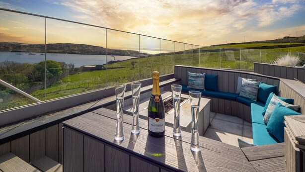 A balcony with a view of a lake, a bottle of champagne, and glasses. - Suaimhneas Villa with Castle and Sea Views (Clifden)