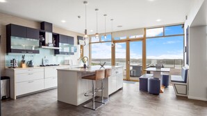 A modern kitchen with a large island, bar stools, and a view of the outdoors. - Suaimhneas Villa with Castle and Sea Views (Clifden)
