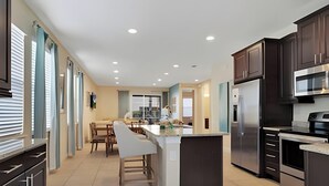 Una cocina moderna con armarios oscuros, electrodomésticos de acero inoxidable y una isla central.