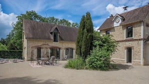 A two-story stone building with a covered patio area featuring outdoor seating. - Architect-designed house for 8 people set in greenery. Near Rambouillet, Paris (Orphin)