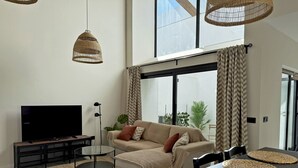 A modern living room with a sofa, a TV, a dining table, and woven pendant lights. - La Solera de Jerez - Ole Solutions (Jerez de la Frontera)