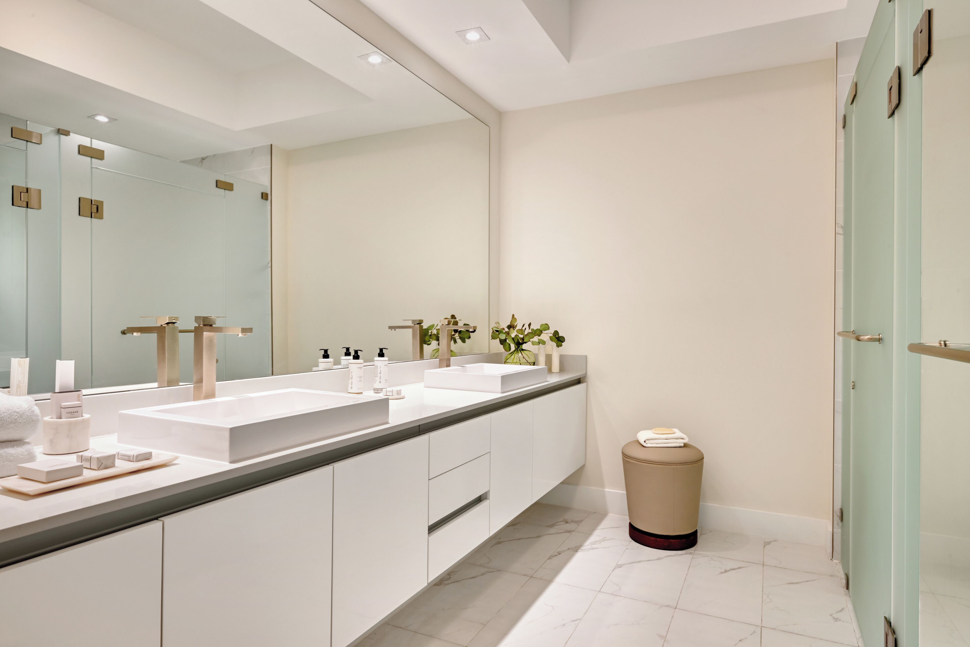 Een moderne badkamer met twee wastafels, een grote spiegel en een prullenbak.