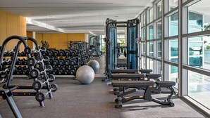Une salle de sport équipée de matériel d’exercice, de supports pour les poids et de grands ballons d’exercice.