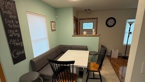A dining area with a table, chairs, and a bench. There is a chalkboard with inspirational quotes on the wall.