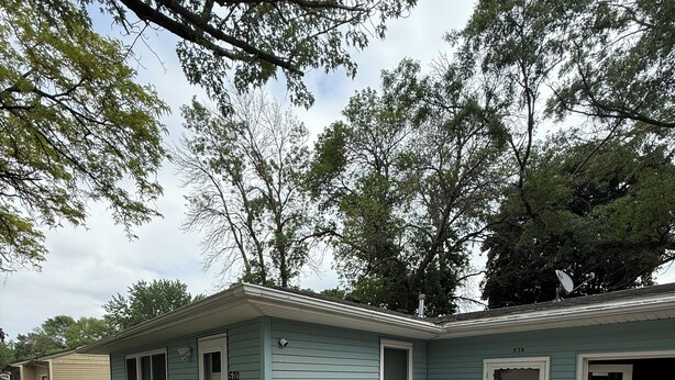 A single-story house with a garage, a patio with a fire pit, and a small garden area.