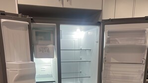 Een moderne keuken met een inbouwkoelkast, een magnetron en een spoelbak.