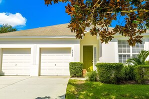 Une maison à deux étages avec un garage, une porte d’entrée et un petit jardin.